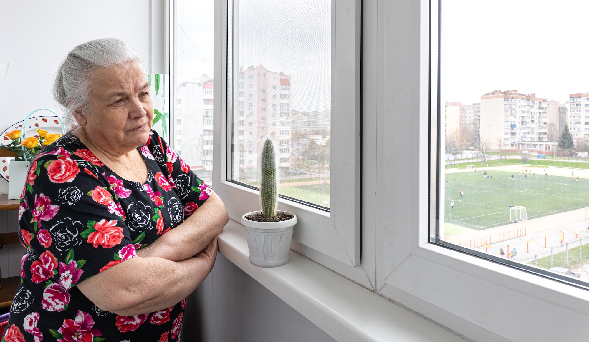 A sad elderly woman looks out the window.