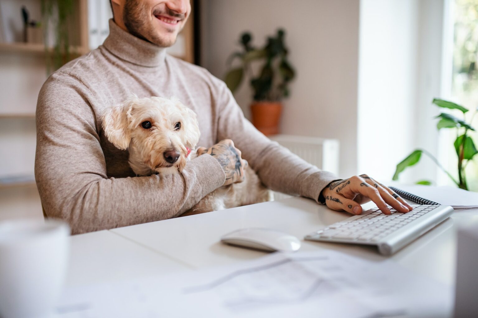 Midsection of businessman with dog sitting at the desk indoors in office.