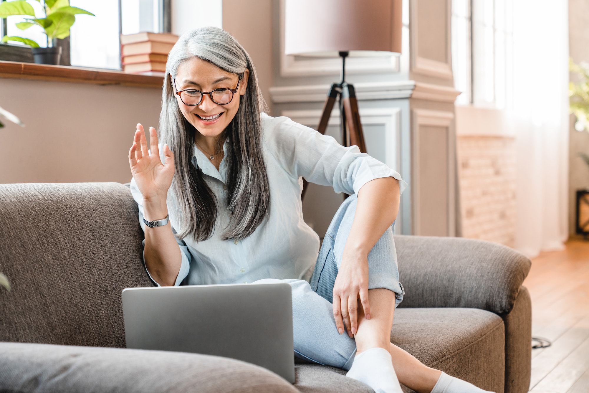 Smart caucasian middle-aged woman having video call on laptop in the living room